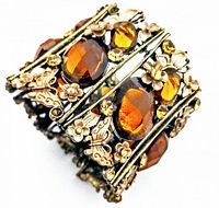 Front view of vintage cuff bracelet showing amber-colored rhinestones and floral butterfly metal accents.