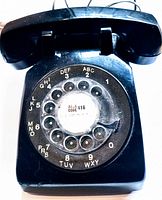 Top view of the vintage black rotary dial telephone showing the dial, handset, and slight wear on the surface.