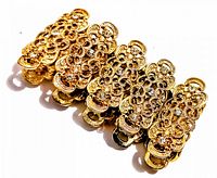 Close-up photo of vintage solid brass stretch bracelet with linked filigree panels and rhinestones.