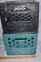 Stacked black and teal milk crates showing side with diamond and hexagonal holes and Sealtest brand