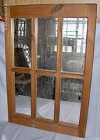 Full front view of pine framed 6-pane mirror showing natural wood grain and knots and aged mirror panes with spotting.