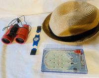 Photo shows the full collection on a white surface including binoculars, fedora hat, Lego Star Wars watch, and Lucky Ball pocket game.