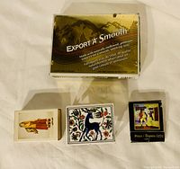Top-down view of the Export 'A' Smooth cigarette box and three matchboxes with decorative designs arranged on a white surface.