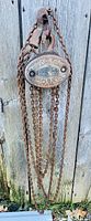 Front view of Morris 1/2 ton manual chain hoist hanging on wooden background, showing front direction of hoist mechanism and chains.