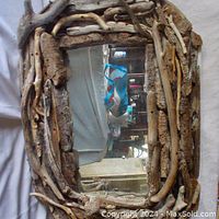 Front view of a handcrafted rectangular mirror with a frame made of various lengths and shapes of natural driftwood pieces in light and dark brown tones, showing the rustic and natural texture of the driftwood.