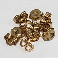 Twelve small 10K yellow gold earring backs in a pile.