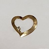 Close-up front view of the 10K yellow gold open heart pendant showing the small stone on the inner lower left.