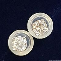 Pair of stud earrings in clear plastic display discs on dark background