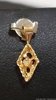 Front and side angles of the yellow gold diamond pendant showing the cut-out diamond shape and small center diamond.