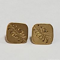 Front view of the 14K yellow gold square stud earrings showing engraved botanical pattern.