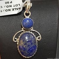 Close-up of the sterling silver pendant showing oval and round blue lapis lazuli stones and silver setting.