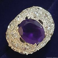 Close-up front view of sterling silver ring with large oval faceted amethyst center and surrounding clear CZ stones.