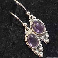 Close-up front view of sterling silver earring with oval cabochon amethyst and silver spheres
