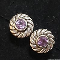 Front angle of one sterling silver amethyst earring showing twisted silver rope motif and faceted round amethyst center stone.