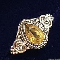 Close-up front view of sterling silver ring with pear-shaped faceted citrine gemstone, showing intricate silver wire and bead detailing.