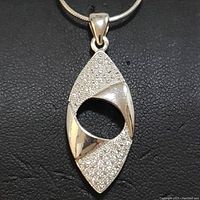 Close-up view of marquise-shaped sterling silver pendant showing pave cubic zirconia stones and polished silver sections.