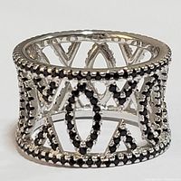 Close-up front angle view of the silver ring showing geometric lattice design accented with black cubic zirconia stones and beaded edges.