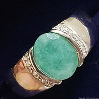 Close-up top view of ring showing oval green CZ center and adjacent white CZ accent stones.