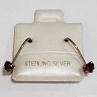 Front view of two sterling silver garnet earrings displayed on white card with 'STERLING SILVER' imprint.