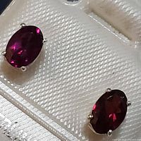 Close-up of the pair of sterling silver garnet stud earrings showing the deep red faceted stones and prong settings.