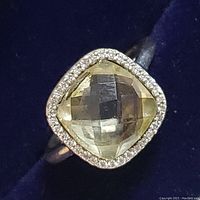 Close-up front view of sterling silver ring with square cushion-cut lemon quartz center stone and clear halo surrounding the stone.