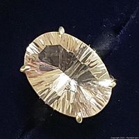 Close-up image showing the oval white quartz gemstone with faceted cuts on a sterling silver ring, highlighting the intricate reflective details and prong setting.