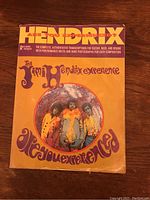 Front cover of the tab book showing title and a circular color photo of Jimi Hendrix and band members on orange background.