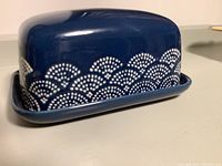 Butter dish front side showing blue ceramic body with white dotted scalloped pattern covering the lower half and base tray visible beneath