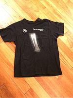 Full view of the black Foo Fighters 2015 concert t-shirt laid flat on wooden floor