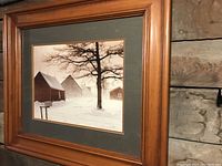 Framed winter landscape print in wood frame on wall showing full artwork and frame.