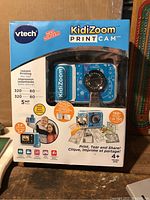 Box front showing blue KidiZoom PrintCam camera and marketing details including instant printing and 5 megapixels.