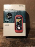 Photo of Magellan Triton 400 handheld GPS device in original box showing front of packaging with product image and key features.