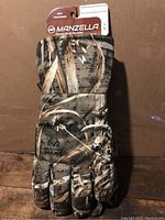 Glove front view showing marshland camouflage pattern and adjustable wrist strap with tag visible.