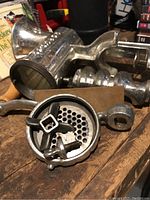 Close-up of the metal meat grinder showing the grinding blade, grinding plates, and attachment screw.