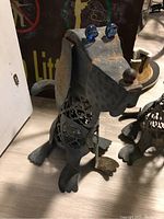 Single metal dog art sculpture showing the textured metal, blue glass eyes, cut-out hollow body, floppy ears, and curled tail.