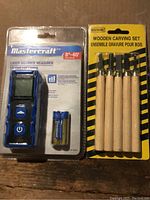 Photo showing Mastercraft laser distance measurer in packaging alongside wooden carving set with 5 carving tools, all new.