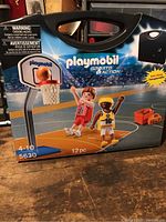 Box front showing Playmobil Sports & Action basketball set in original packaging with illustrations of players and court.