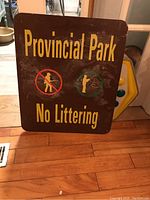 Front view of the rectangular Provincial Park sign with 'No Littering' text and fishing icons on a brown background.