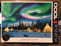 Front of puzzle box showing Northern Lights scene, teepees, and trees under aurora borealis, labeled 'Northern Lights' and '1000 pieces'