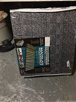 Photo showing reversible mattress inside gray protective bag with label attached describing product features.