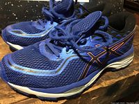Photo of a pair of blue Asics running shoes, right foot side view showing the mesh and side logo.