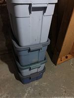 Stacked Rubbermaid storage totes showing all four plastic totes of different colors with lids.