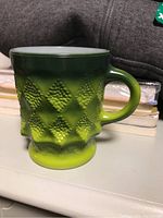 Side view of vintage green ombre Fire King coffee mug showing diamond texture and rounded handle.