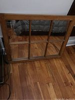 Full view of vintage sash mirror showing wooden frame and mirror panes, placed on hardwood floor.