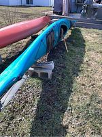 Side view of blue kayak on grass showing deck rigging and overall hull shape