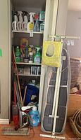 Full view of hall closet with cleaning supplies, mop, ironing board, bucket, and other items