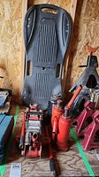 Photo showing the entire lot including the hydraulic trolley jack, three jack stands, and car creeper arranged together on a wooden floor with plywood wall background.
