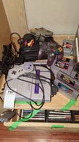 Top view showing SNES and N64 consoles, controllers, cables, and stacks of game cartridges