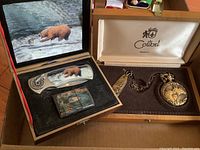 Photo showing the bear-themed lighter and cutter set inside a case featuring a bear in a river scene
