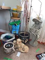 Group view of statue, puppies, planters, stand, soil bag